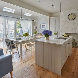 dining area with white wall with wooden floor and white dining table and kitchen counter