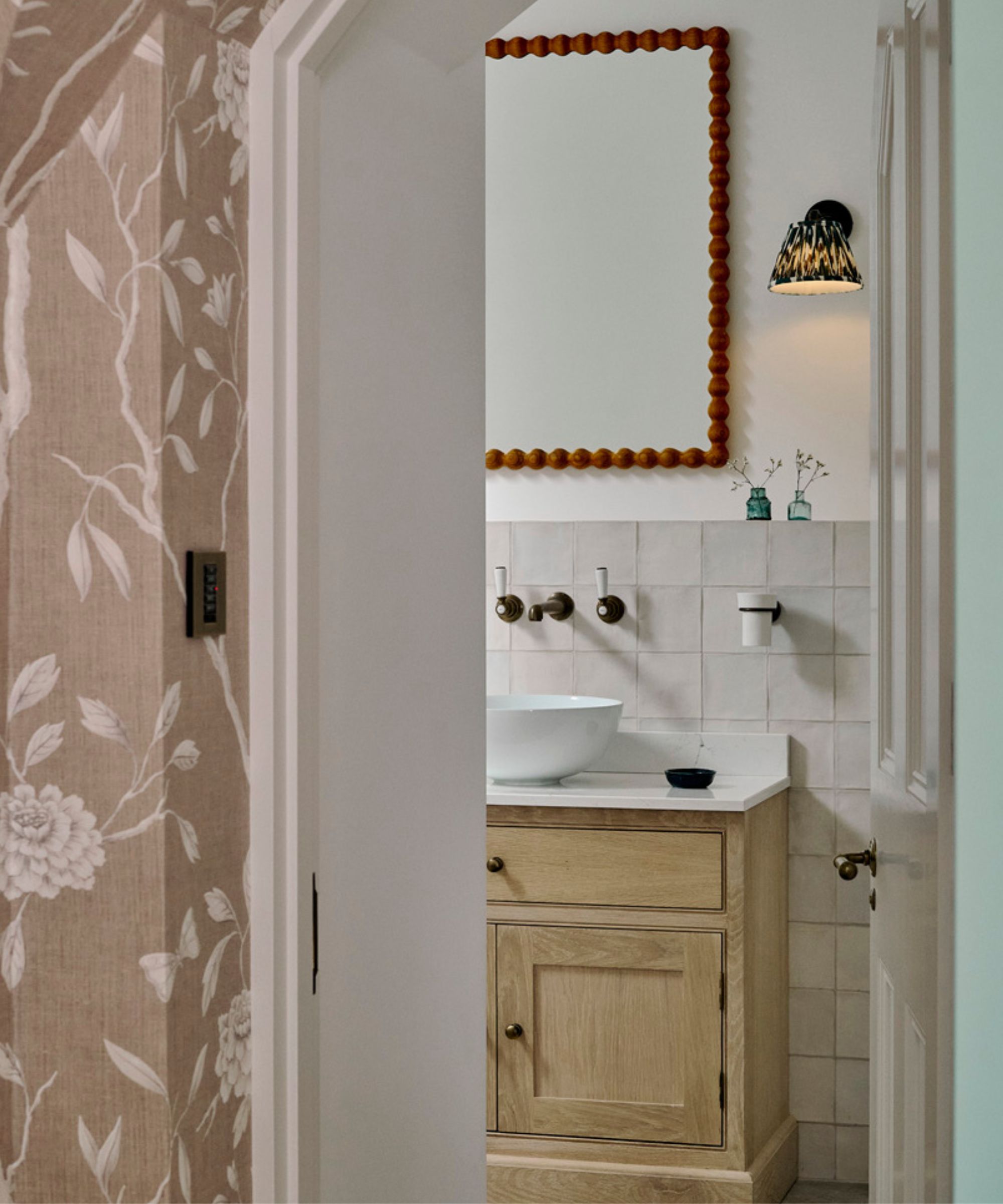 A wood and marble bathroom vanity with a red mirror above