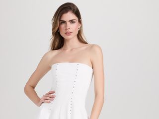 Model wears white strapless minidress.