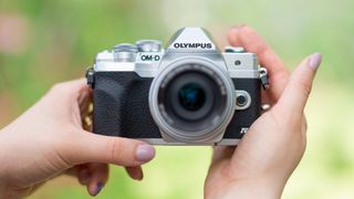 Olympus OM-D E-M10 Mark IV beginner's mirrorless camera being held by our reviewer