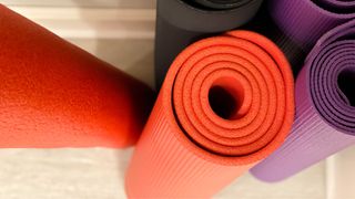 Red yoga mats rolled up next to purple yoga mats