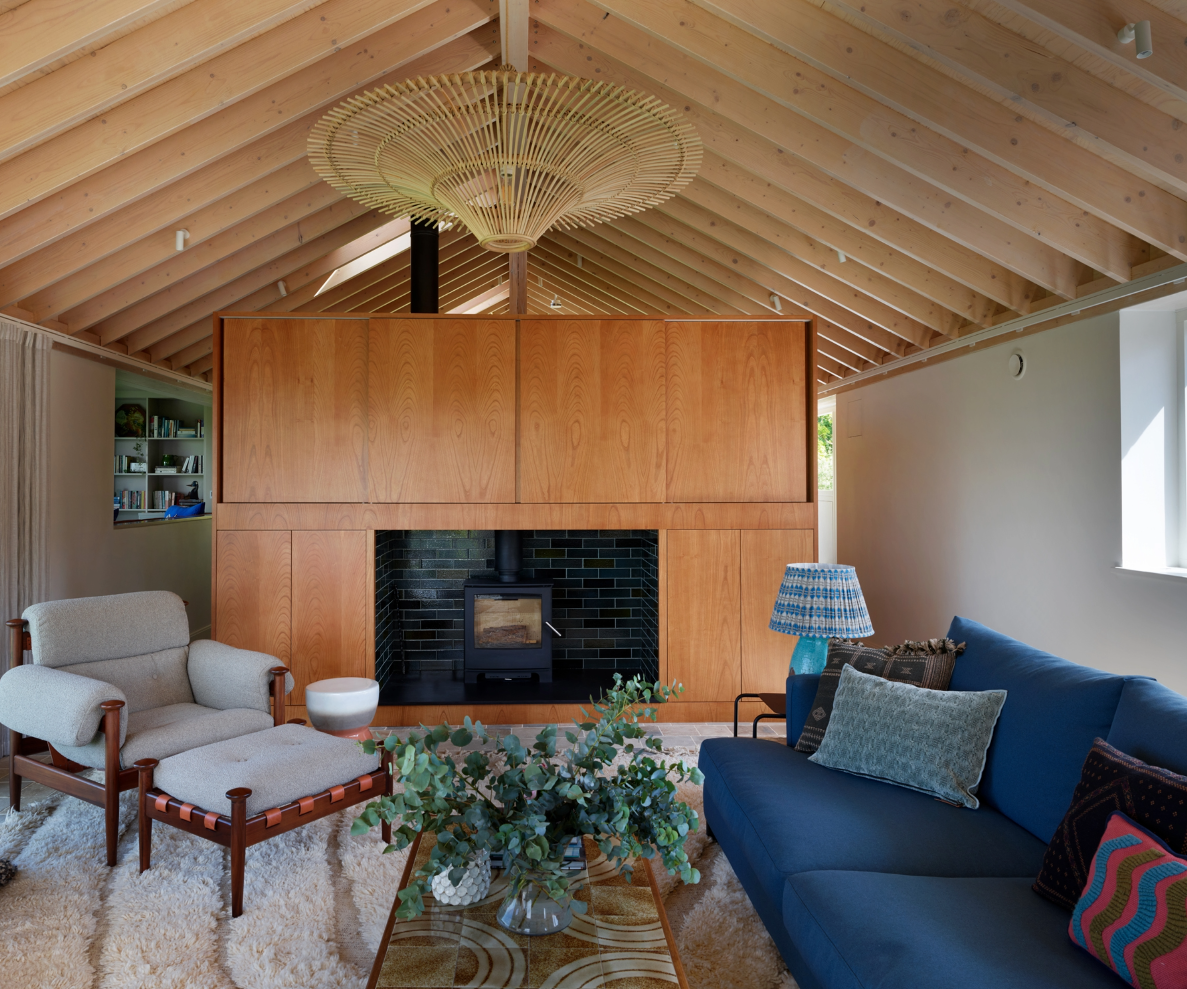 Living area with sofa, chair and log burner, with vaulted ceilings