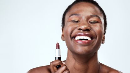 Woman smiling holding a lipstick depicting easy makeup looks