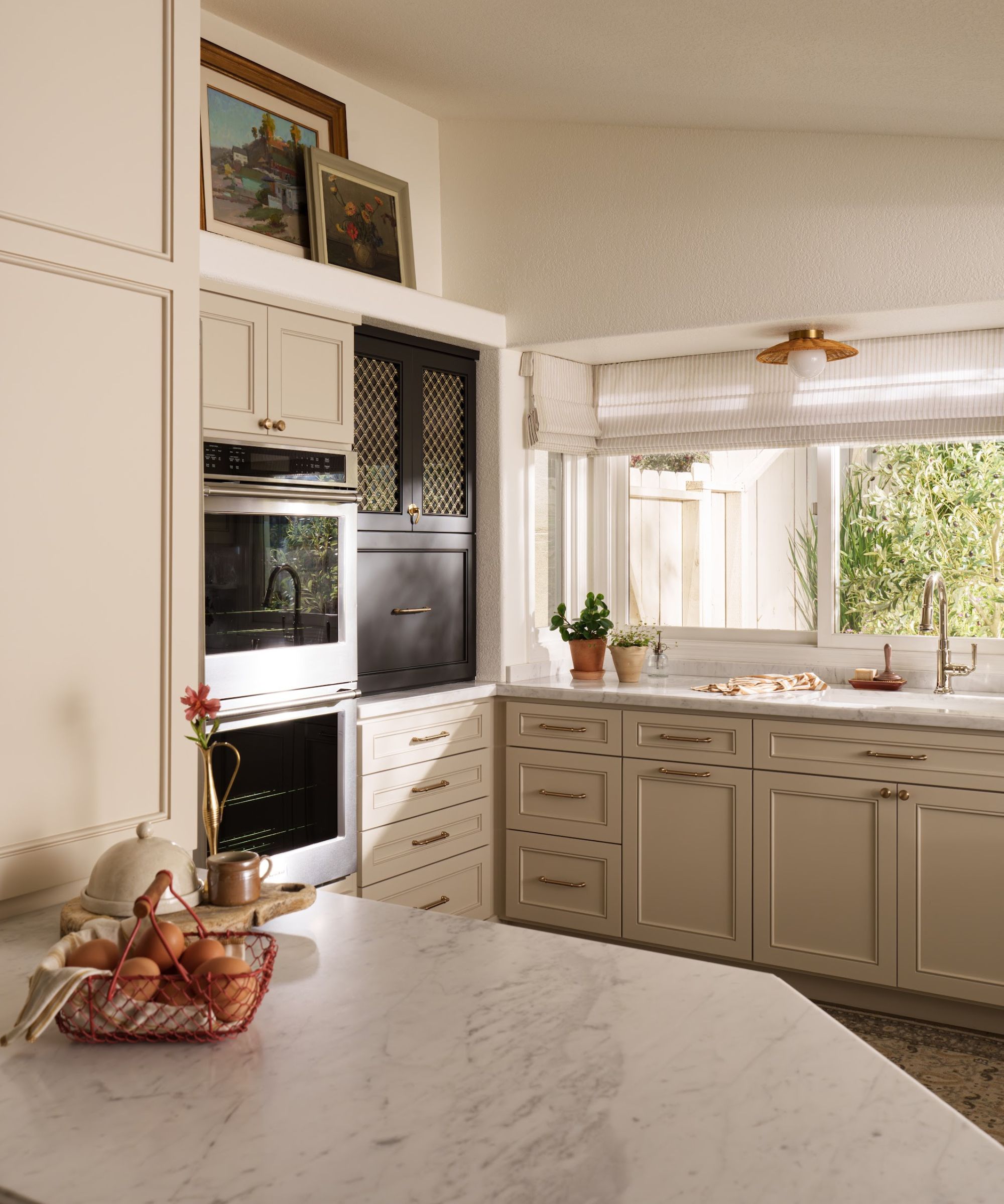 A small neutral kitchen with brass hardware and art as decor