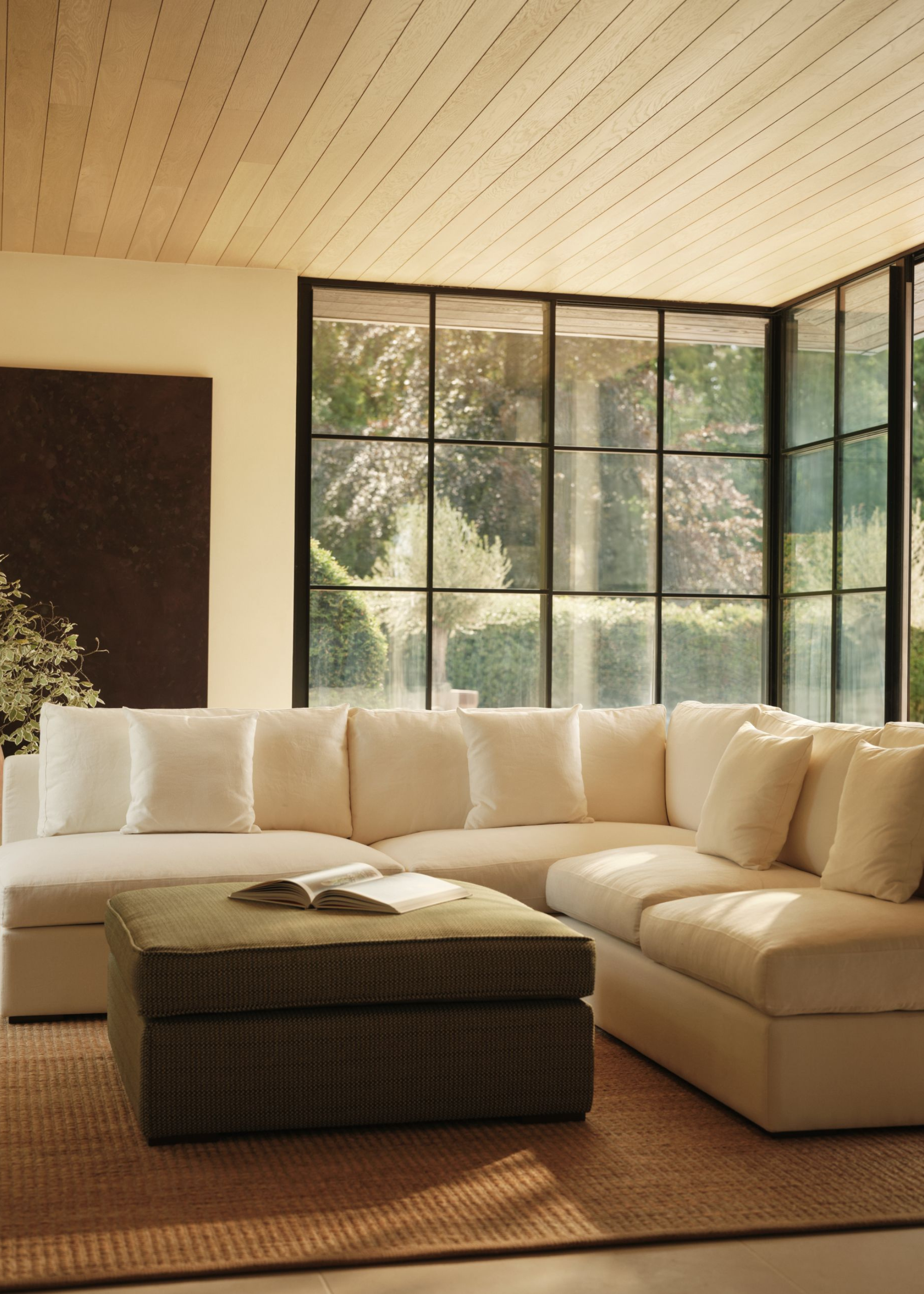 a sitting area in timber clad pool house with large white L shaped sofa