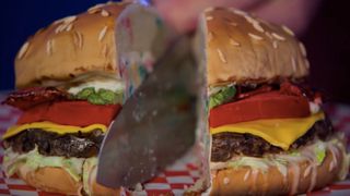 A knife cutting through a burger cake in Is It Cake?