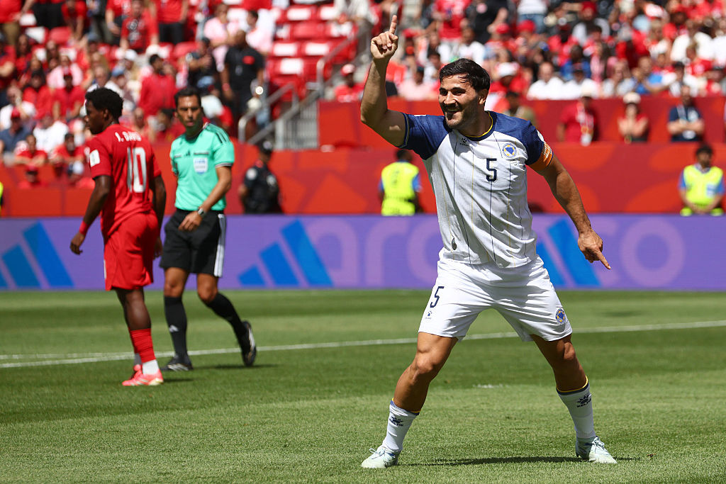Sead Kolasinac against Canada, pointing a finger in the air and smiling.