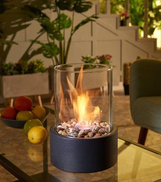 A small firepit with a glass container on a coffee table in a living room