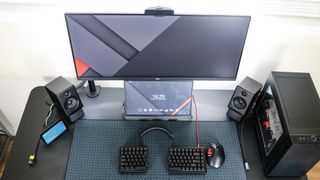 An overhead view of desk setup with an ultrawide monitor with a portable monitor underneath it