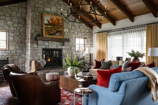 living room with stone wall fireplace with red, brown and blue furnishings