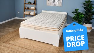 The Saatva Classic Luxury Innerspring Hybrid mattress photographed in a blue bedroom, with a blue Tom's Guide Price Drop image overlaid on the bottom right hand corner of the image