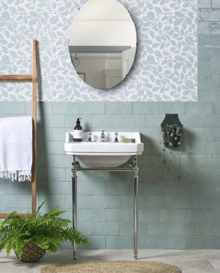 bathroom with soft green tile and oak leaf wallpaper