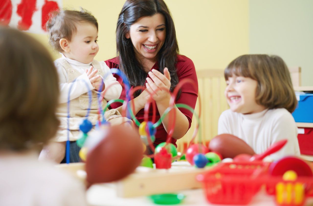 three little girls and female teacher in kindergarten