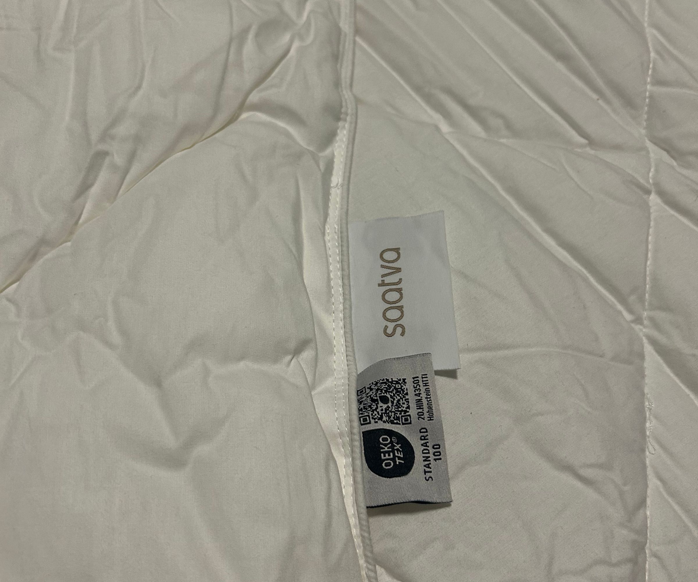 Close up shot of a Saatva Down Alternative comforter with labels showing