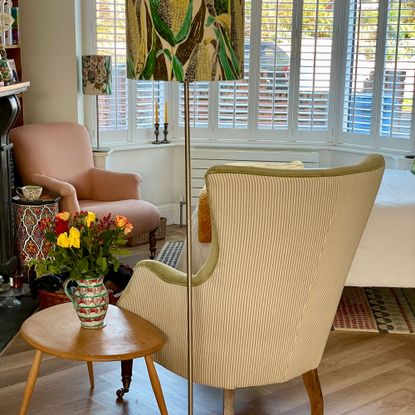 Corner of room with two armchairs, table lamp and side table with vase of flowers