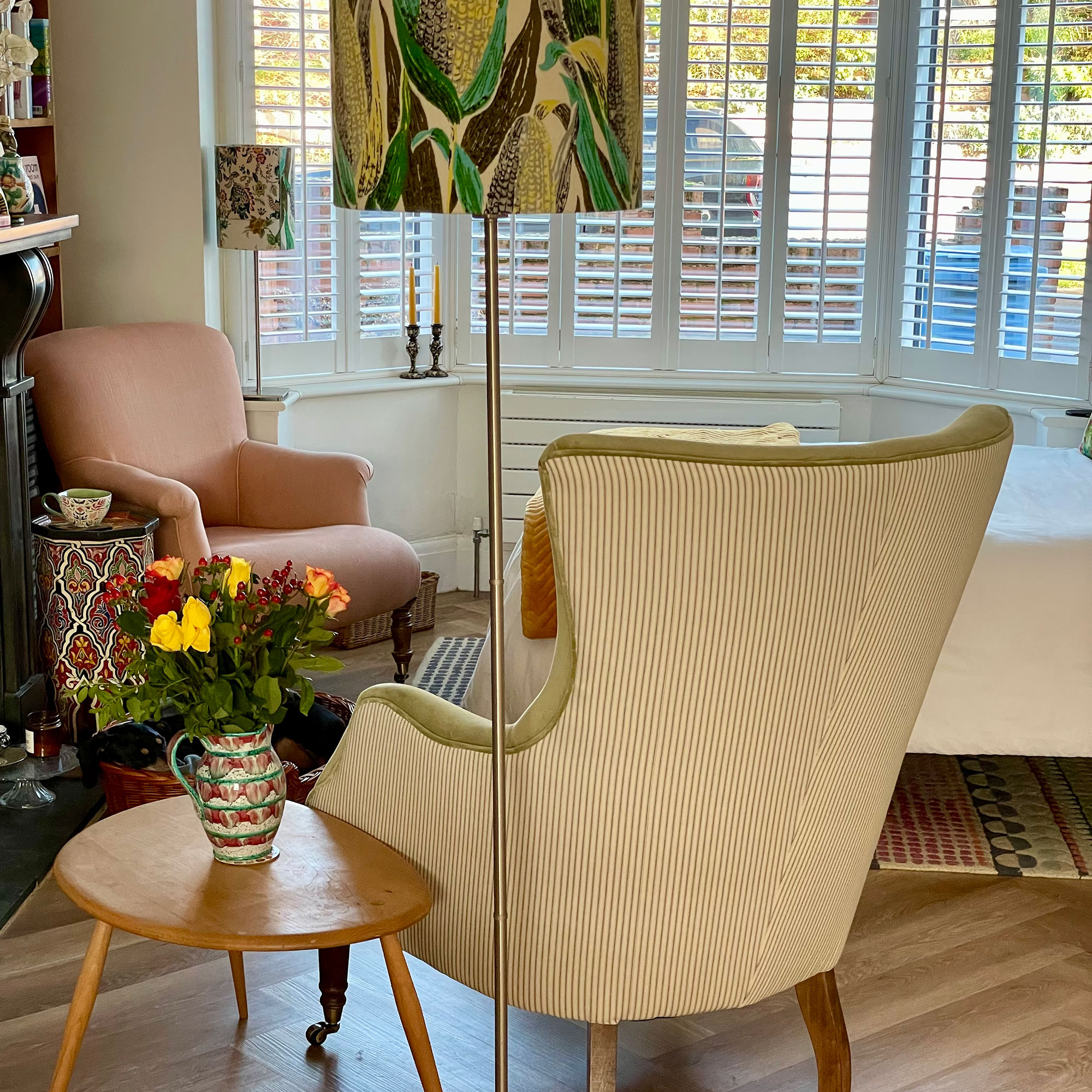 Corner of room with two armchairs, table lamp and side table with vase of flowers