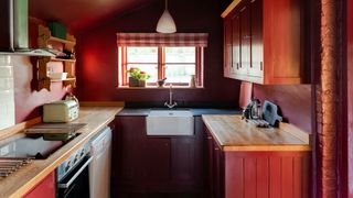 red cottage style kitchen with red walls and red cabinets paired with wooden worktops