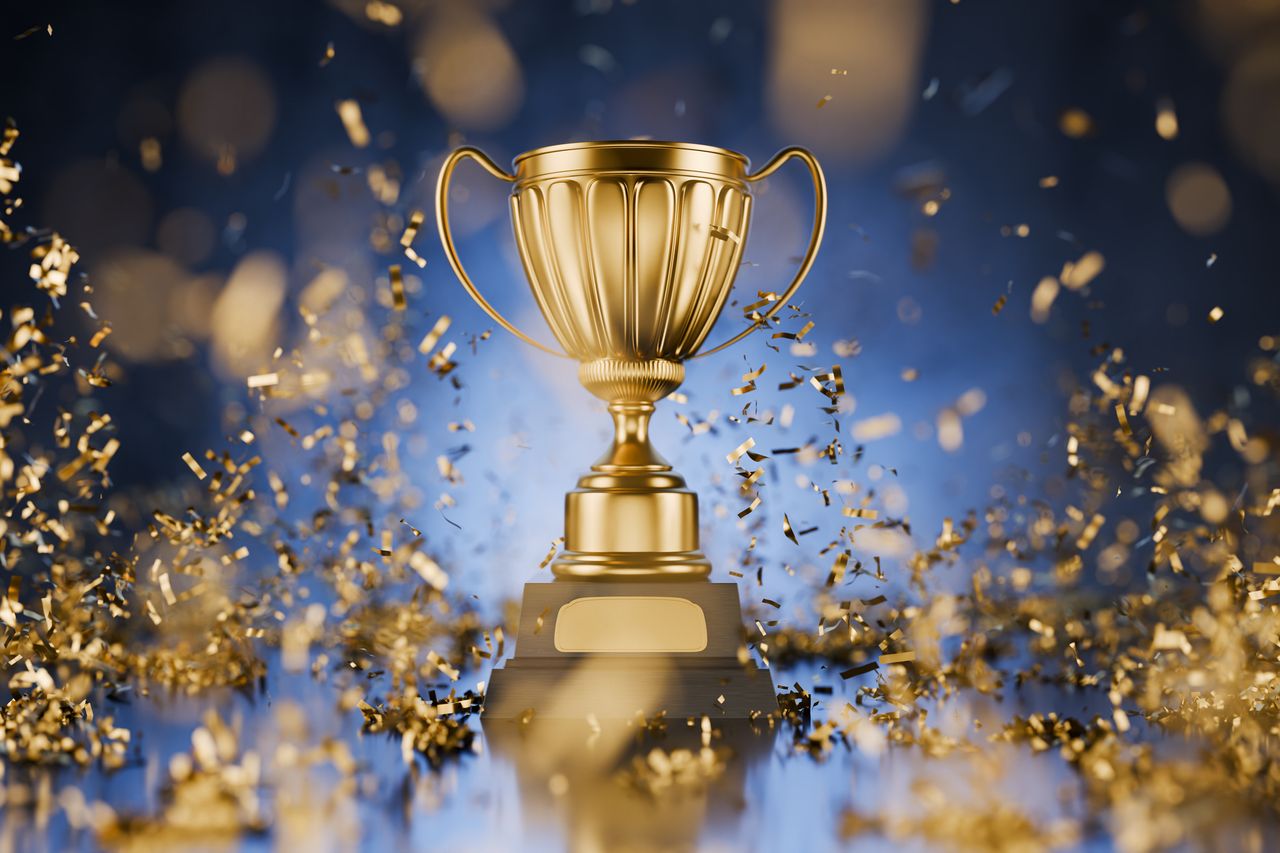 A shiny gold winner&#039;s cup on a blue background symbolizes victory and success in competition.