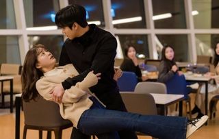 a woman falls into a man's arms in an office in the k-drama 'Business Proposal.'