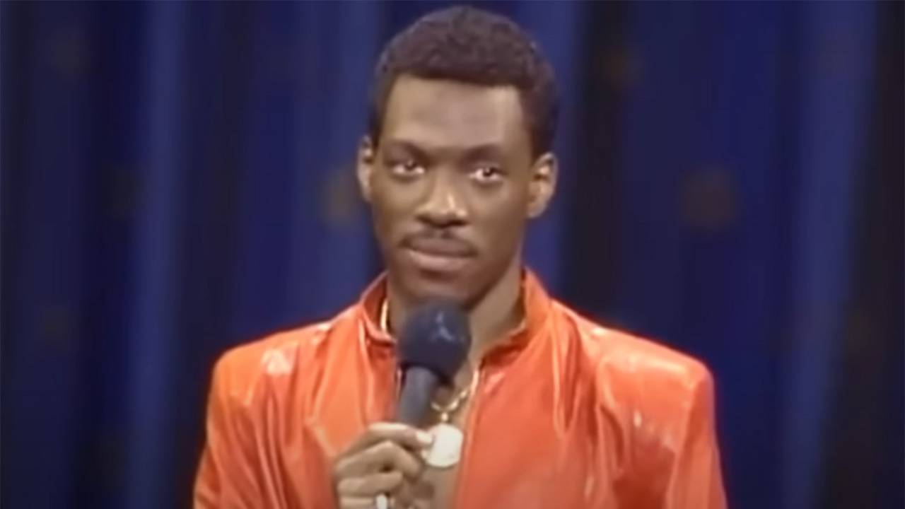 Eddie Murphy in a red jacket looking serious in his Delirious comedy special.