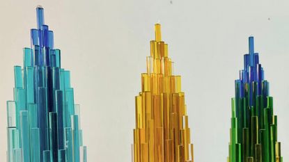 Three Yinka Ilori glass trophies in blue, yellow and green/blue