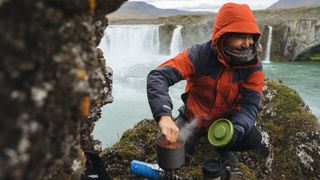 Man cooking in pot over camping stove