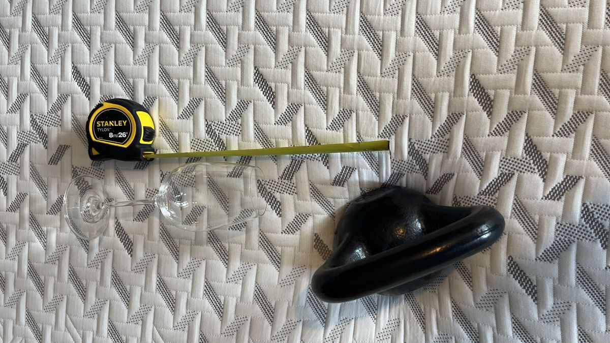 wine glass fallen next to 10lbs kettlebell with tape measure on the side