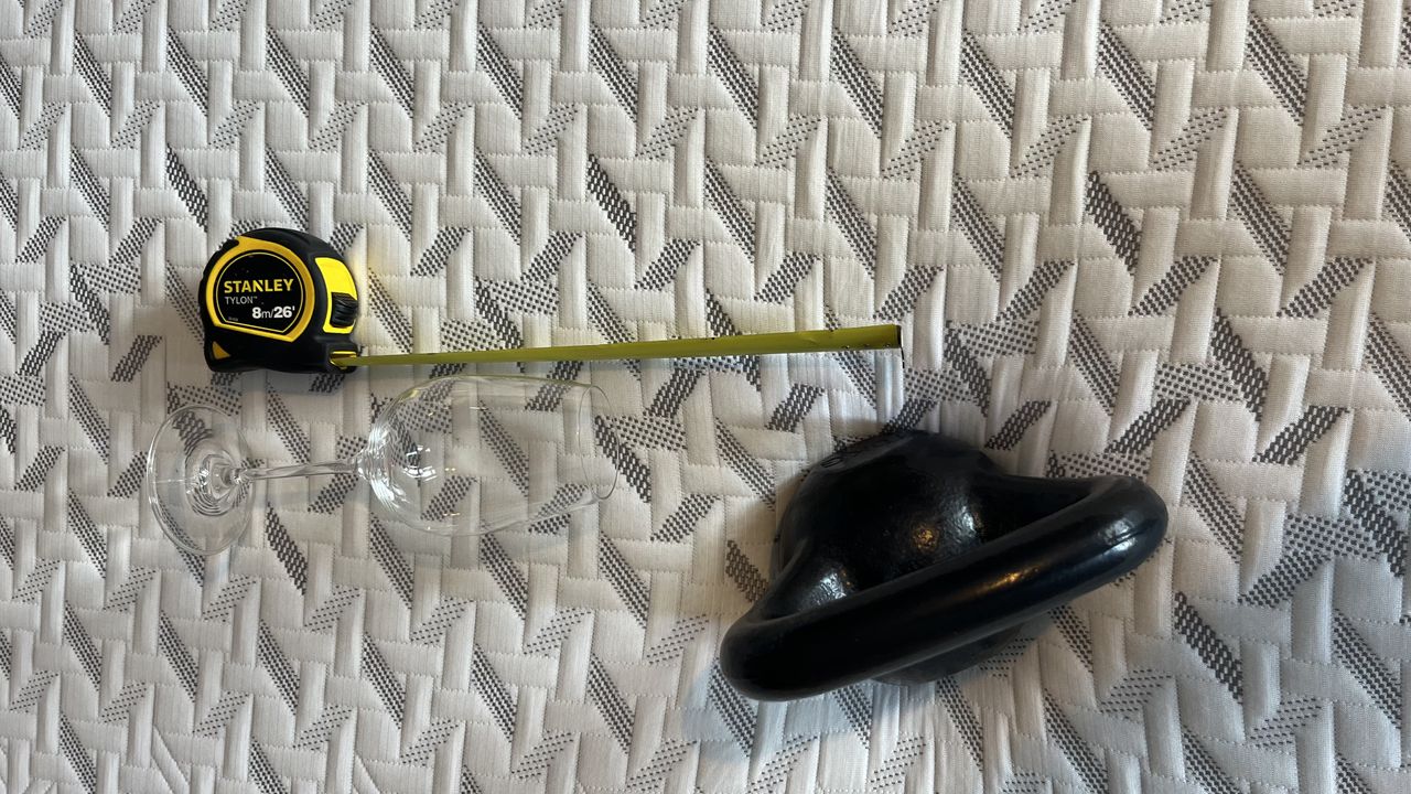 wine glass fallen next to 10lbs kettlebell with tape measure on the side