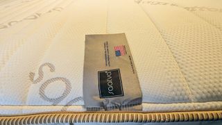 A close up of the Saatva Memory Foam Hybrid mattress showing its label