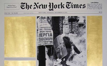 A copy of the New York Times. Other than the image and heading, all other text has been covered in gold leaf