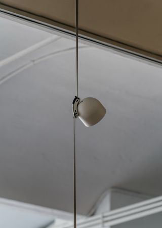 A grey semi spherical light hanging from a straight rope in the same shade
