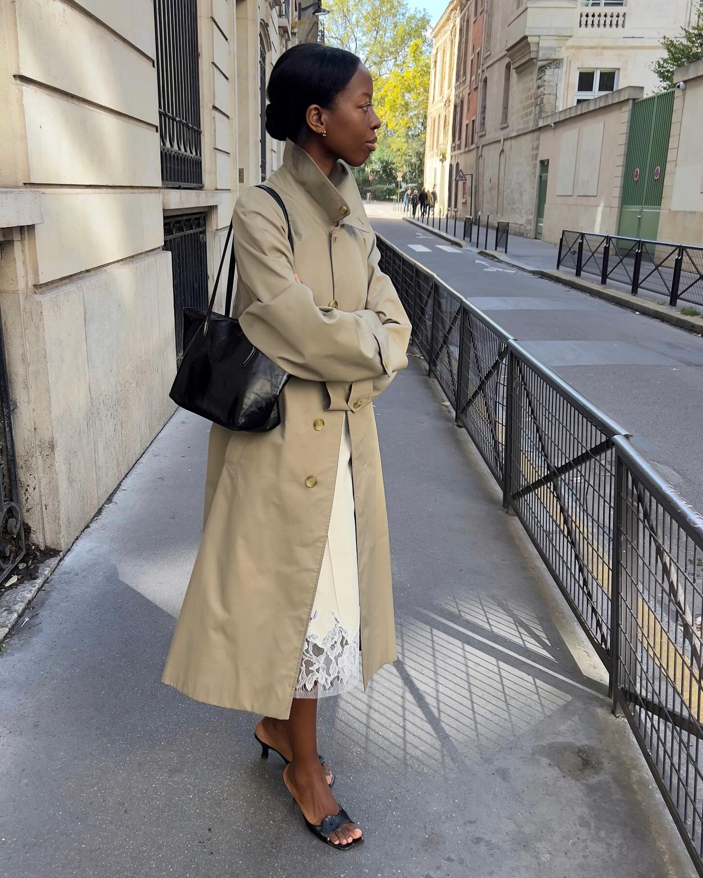 @sylviemus_ wearing a trench coat, lace-trim skirt, and kitten heels