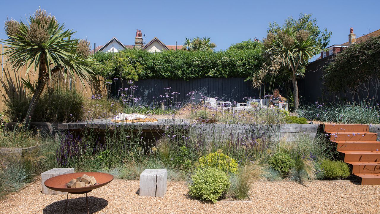 garden with grasses, gravel a firepit and garden steps up to a patio area