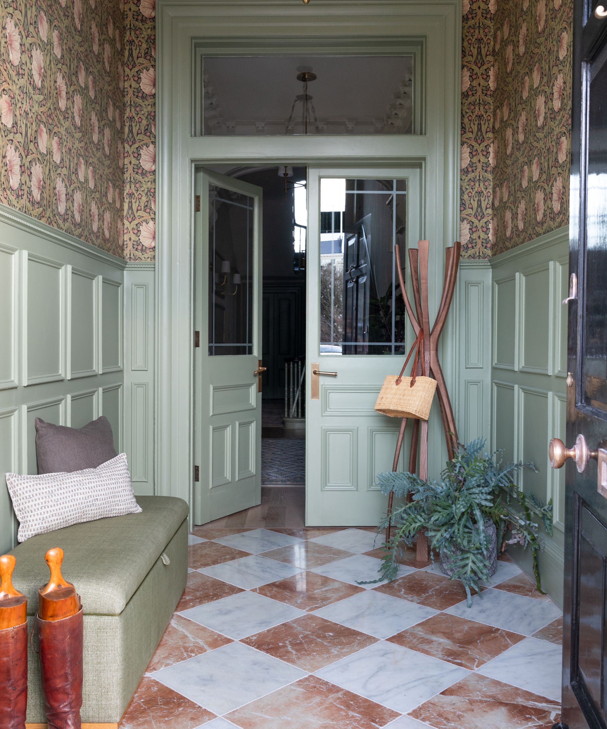Elegant hallway with sage green woodwork, floral wallpaper and checkerboard marble floor, blending period features with rich, heritage styling.