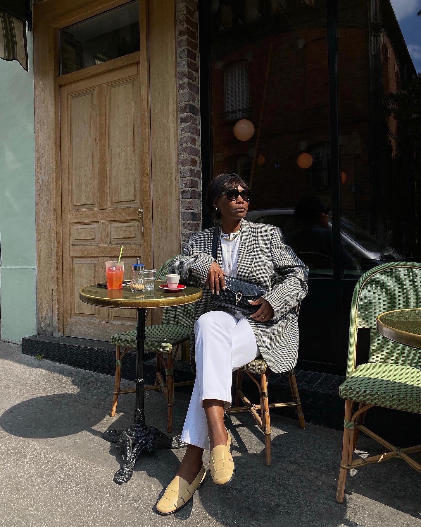 woman wears cream shoes with white jeans at a french cafe