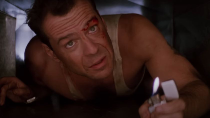 Bruce Willis as John McClane holding up a lighter while crawling through a vent during one of the best movies on Hulu, Die Hard. 