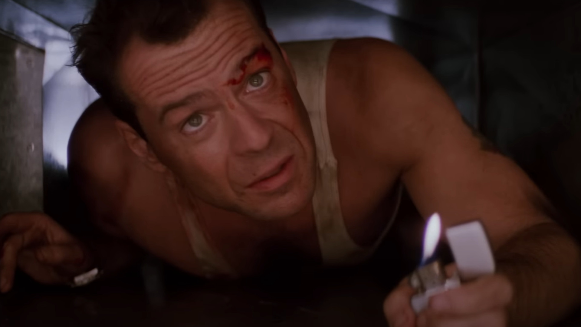 Bruce Willis jako John McClane trzymający zapalniczkę podczas czołgania się przez otwór wentylacyjny w jednym z najlepszych filmów na Hulu, Szklanej pułapce.