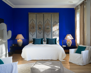 Yves Klein® Shade of blue in bedroom with wall hanging above bed and complementary teal throw cushions in the space