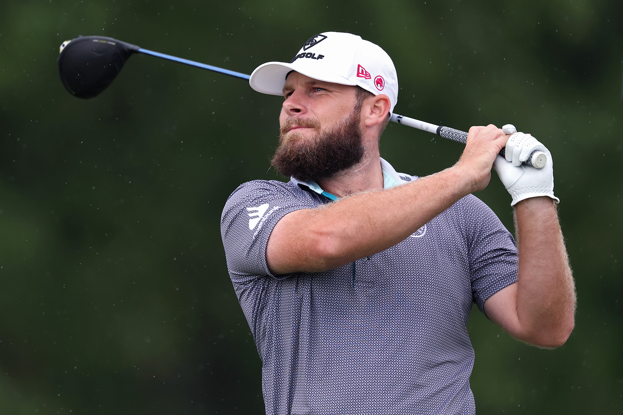 Tyrrell Hatton in the finish position of his golf swing, watching the ball as it travels wearing his LIV Golf Legion XIII clothing