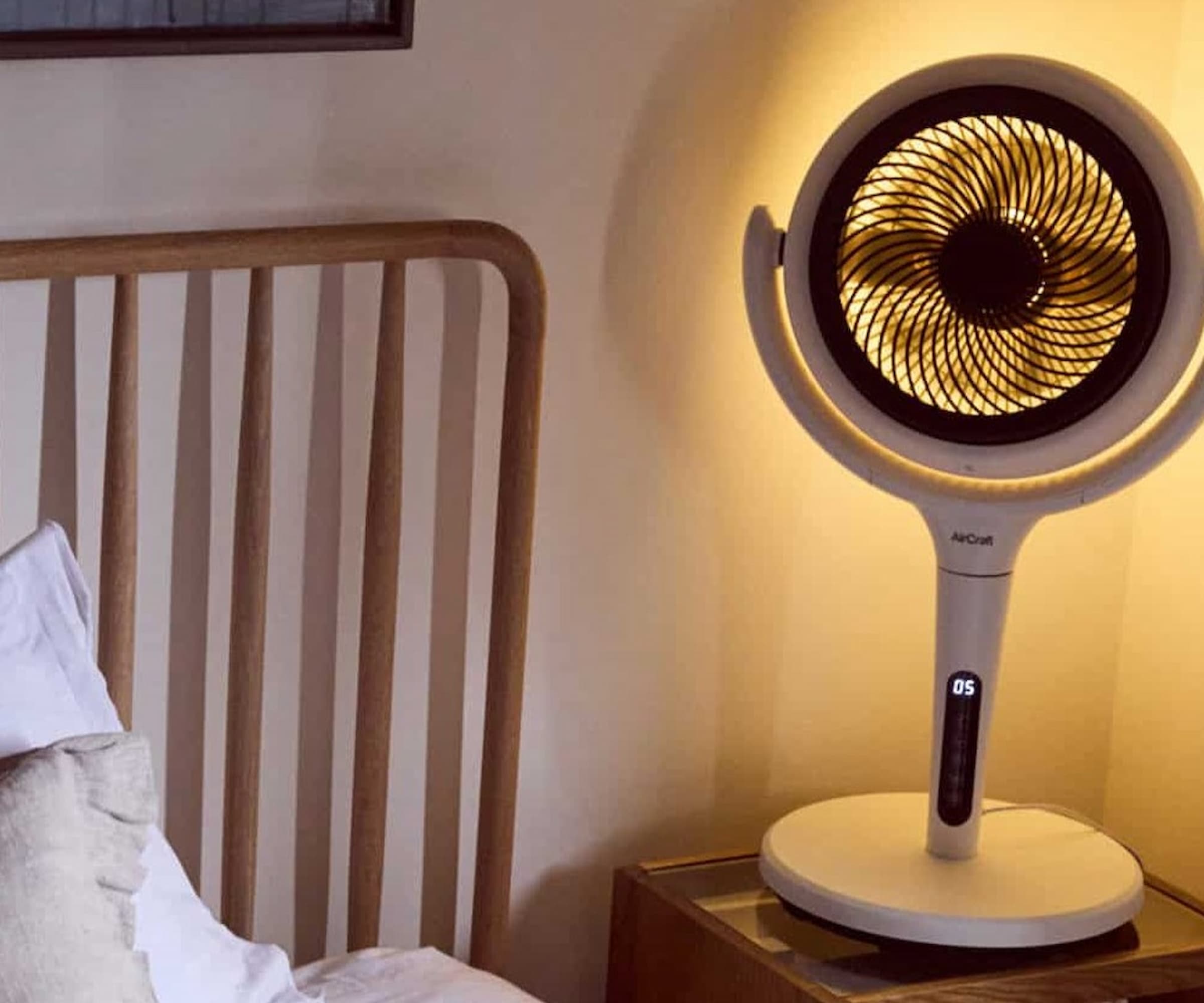 An air circulator next to a bed with ambient light