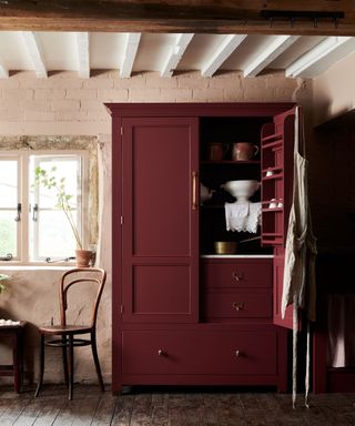 burgundy deep red painted pantry cabinet in a neutral kitchen with rustic ceiling beams