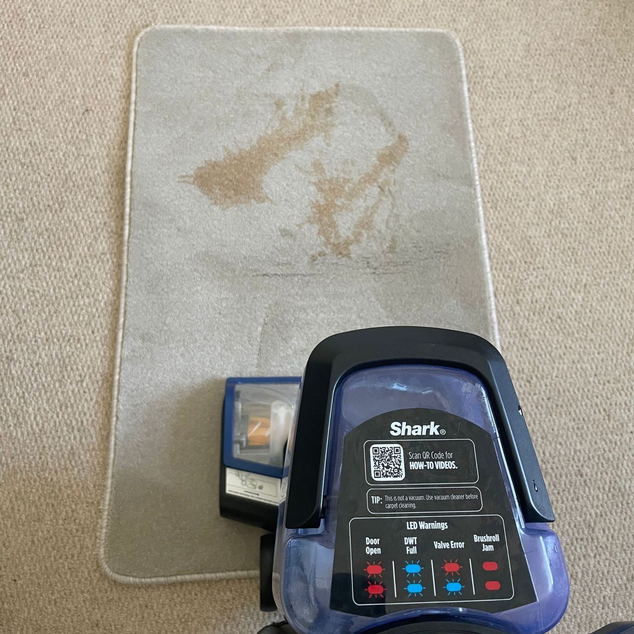 Tea stain on a carpet sample, with the Shark CarpetXpert EX250UK on top of it