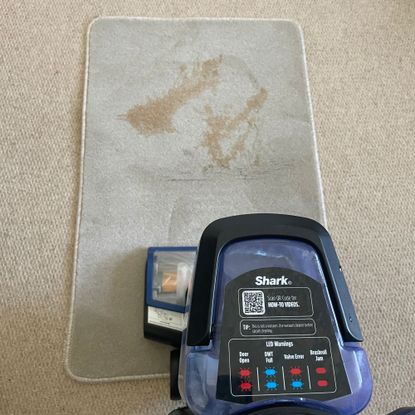Tea stain on a carpet sample, with the Shark CarpetXpert EX250UK on top of it