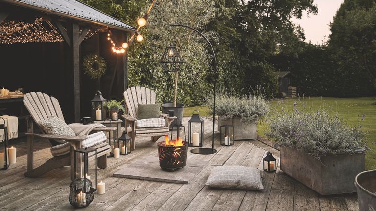 Fire pit ideas – outdoor deck with fire pit and garden chairs and lanterns