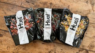 Three ready meal packets from Huel arranged in a line on a table