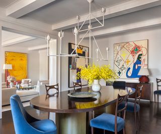 dining room with blue chairs and view to living room with art