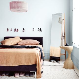bedroom with white wall and wooden floor and floor mirror