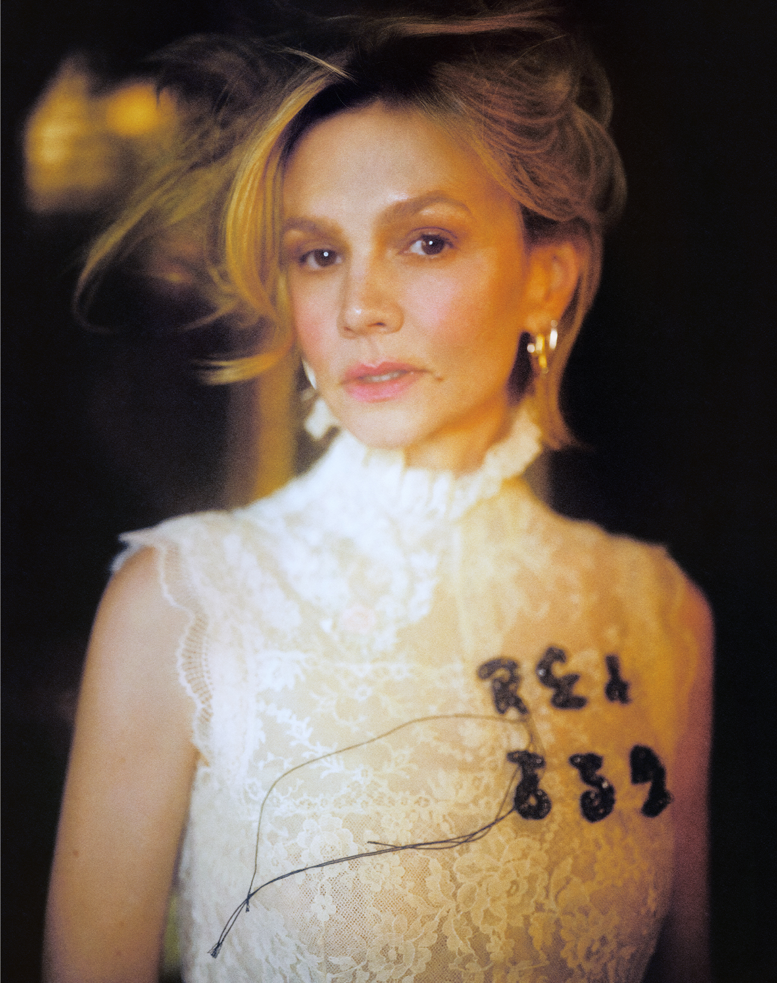 Carey Mulligan for Who What Wear's April cover story posing in a white lace dress with black lettering on the right side of her chest.