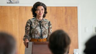 Shohreh Aghdashloo standing at a lectern in The Flight Attendant