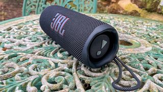 JBL Flip 6 speaker outside on garden table showing passive speaker radiators at end of tube